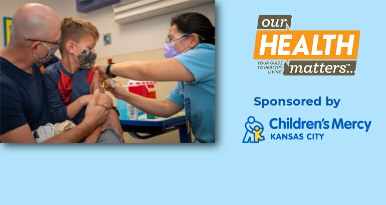 A child receives a vaccine from a nurse while holding the hand of their parent. Sponsored by Children's Mercy